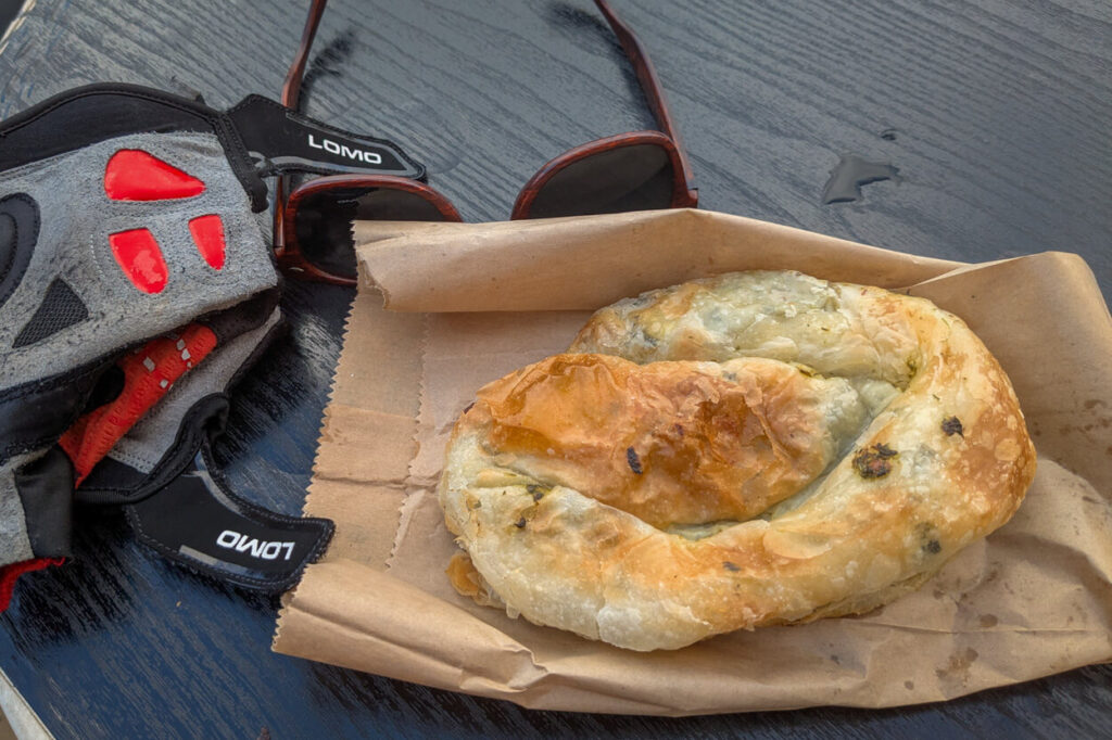 Cyclists trying a burek on Trans Dinarica.